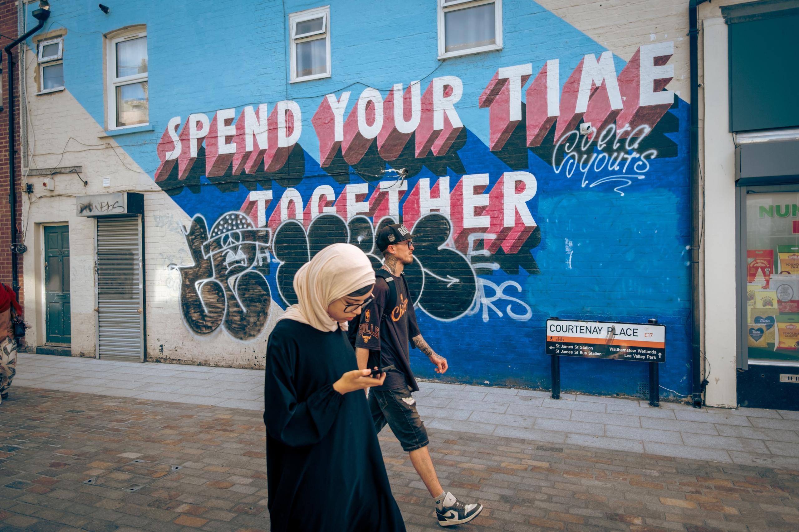 Hijabi and skater. Walthamstow High Street, London.